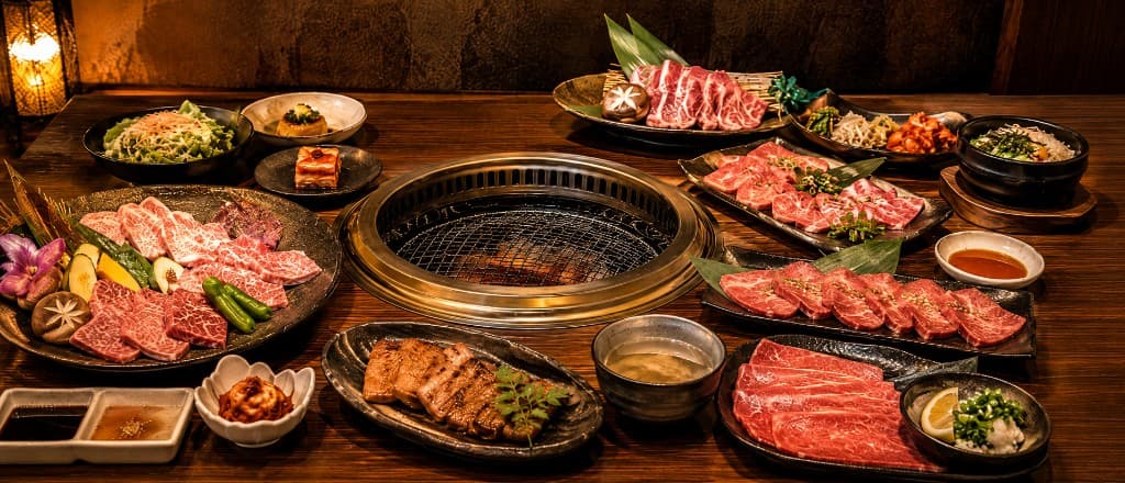 焼き網を囲んで霜降り肉や料理が並ぶ卓の写真